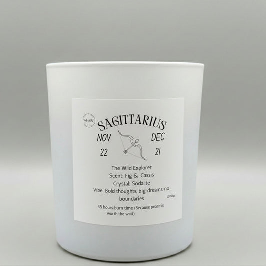 White candle with a label indicating the zodiac sign Sagittarius on a gray background