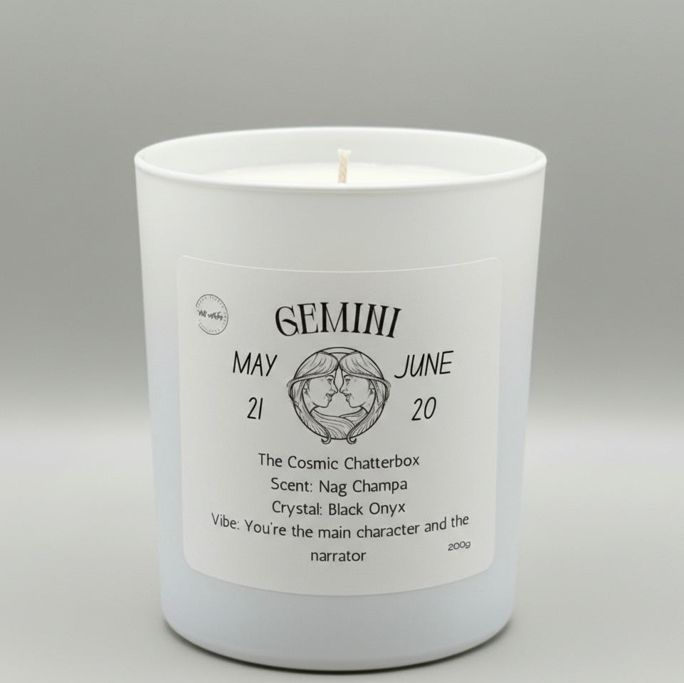 White candle with a label detailing the Gemini zodiac sign on a gray background