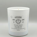 White candle with a label detailing the Gemini zodiac sign on a gray background