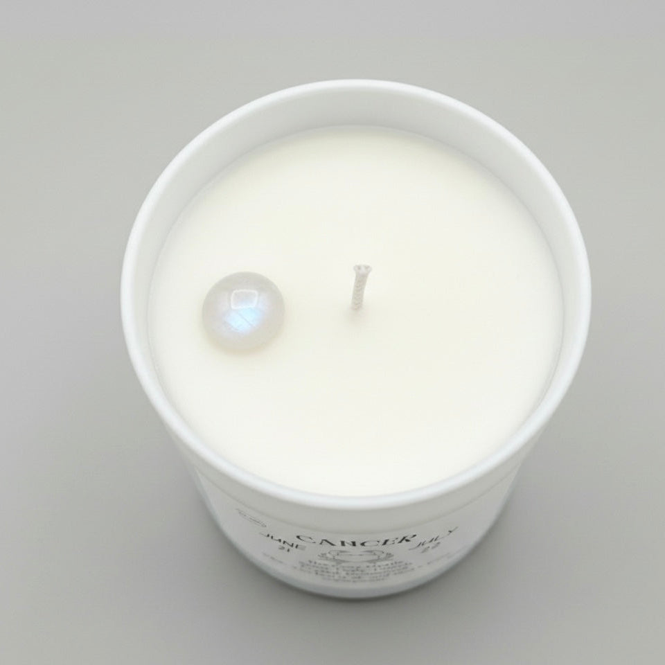 White candle in a glass jar with a label on a gray background