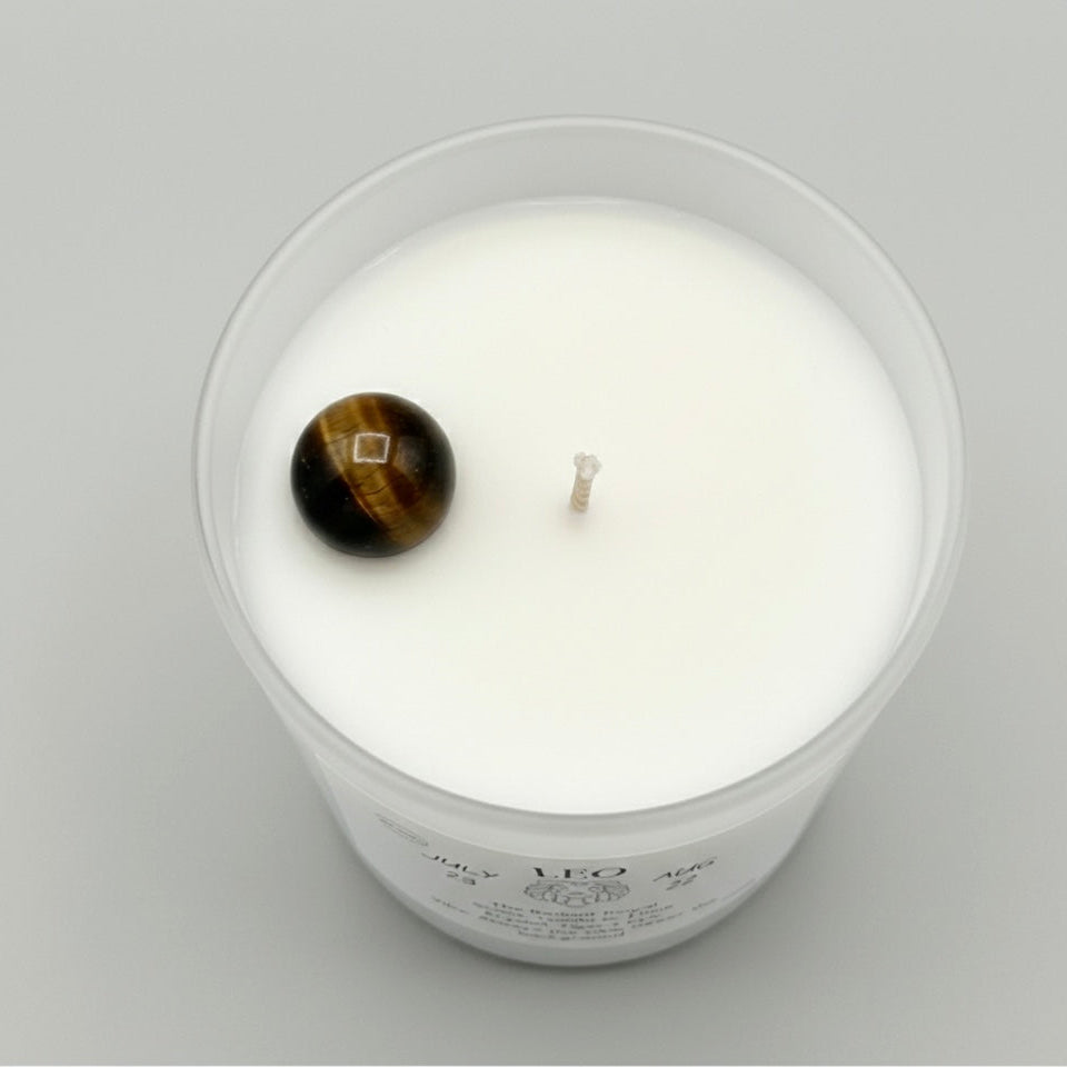 White candle with a tiger's eye stone on a gray background