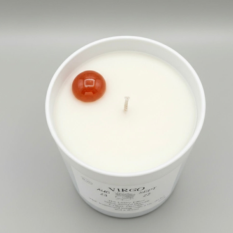 Candle in a white container with a red sphere on top against a gray background