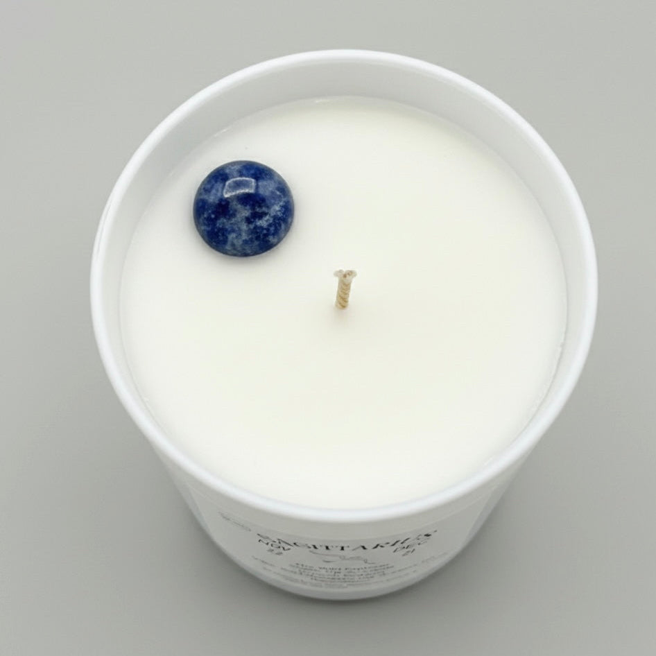 Candle in a white container with a blue gemstone on a gray background