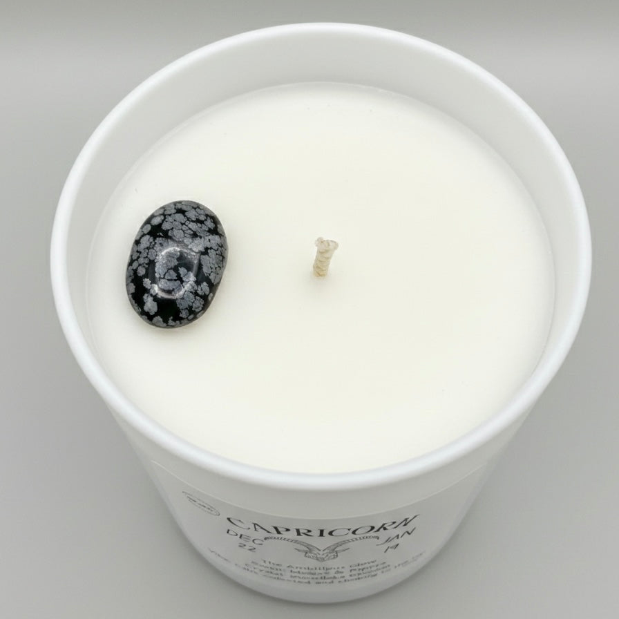 Candle in a white container with a decorative stone on a gray background