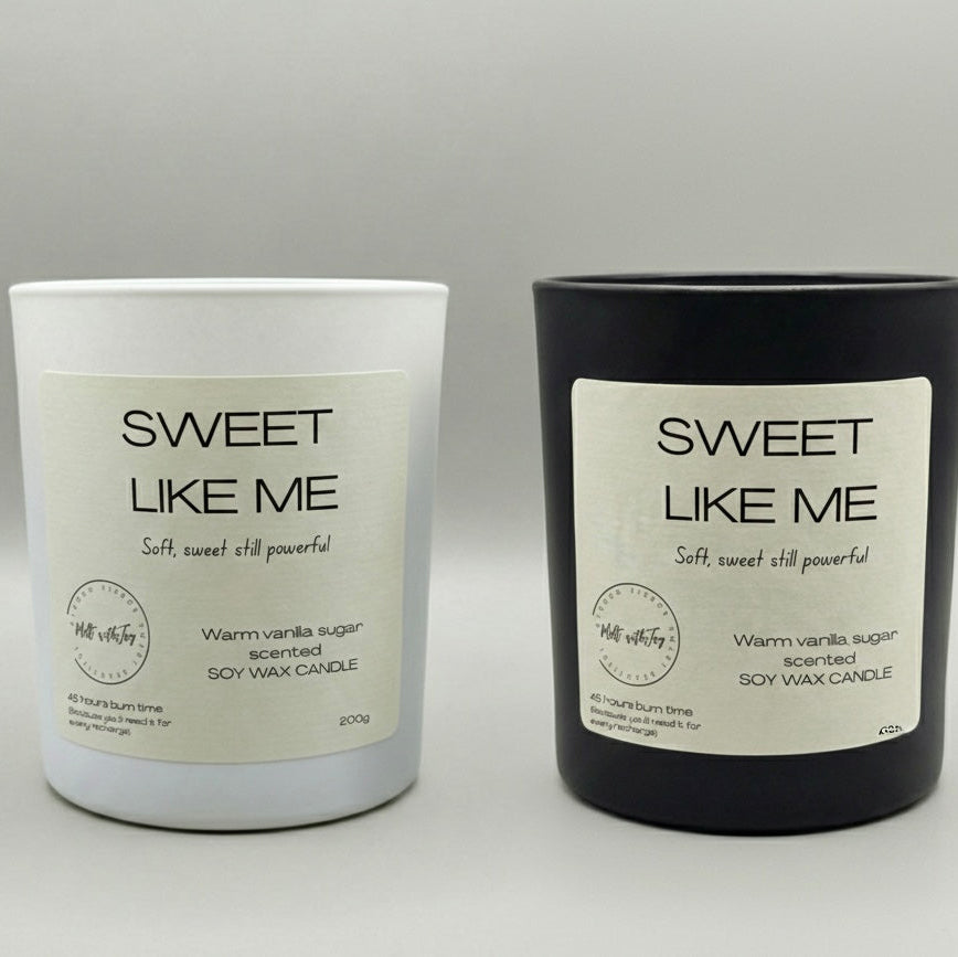 Two candles, one white and one black, with 'Sweet Like Me' labels on a gray background.