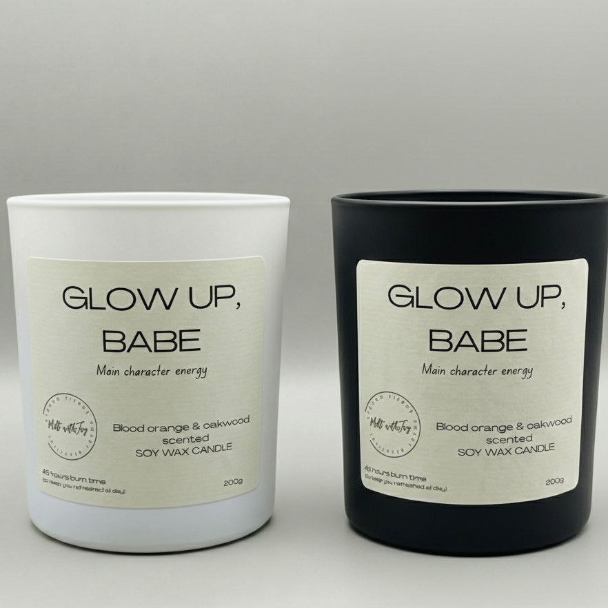 Two candles, one white and one black, with 'Glow Up, Babe' labels on a gray background.