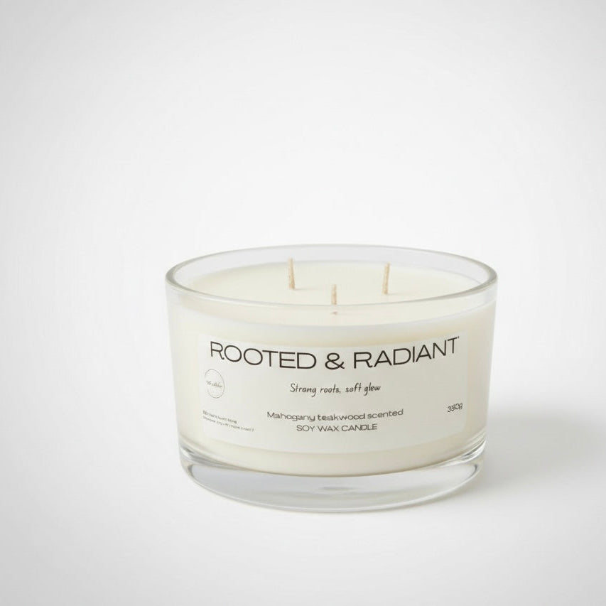 Candle with 'Rooted & Radiant' label on a white background