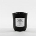 Black candle with a white label on a light gray background