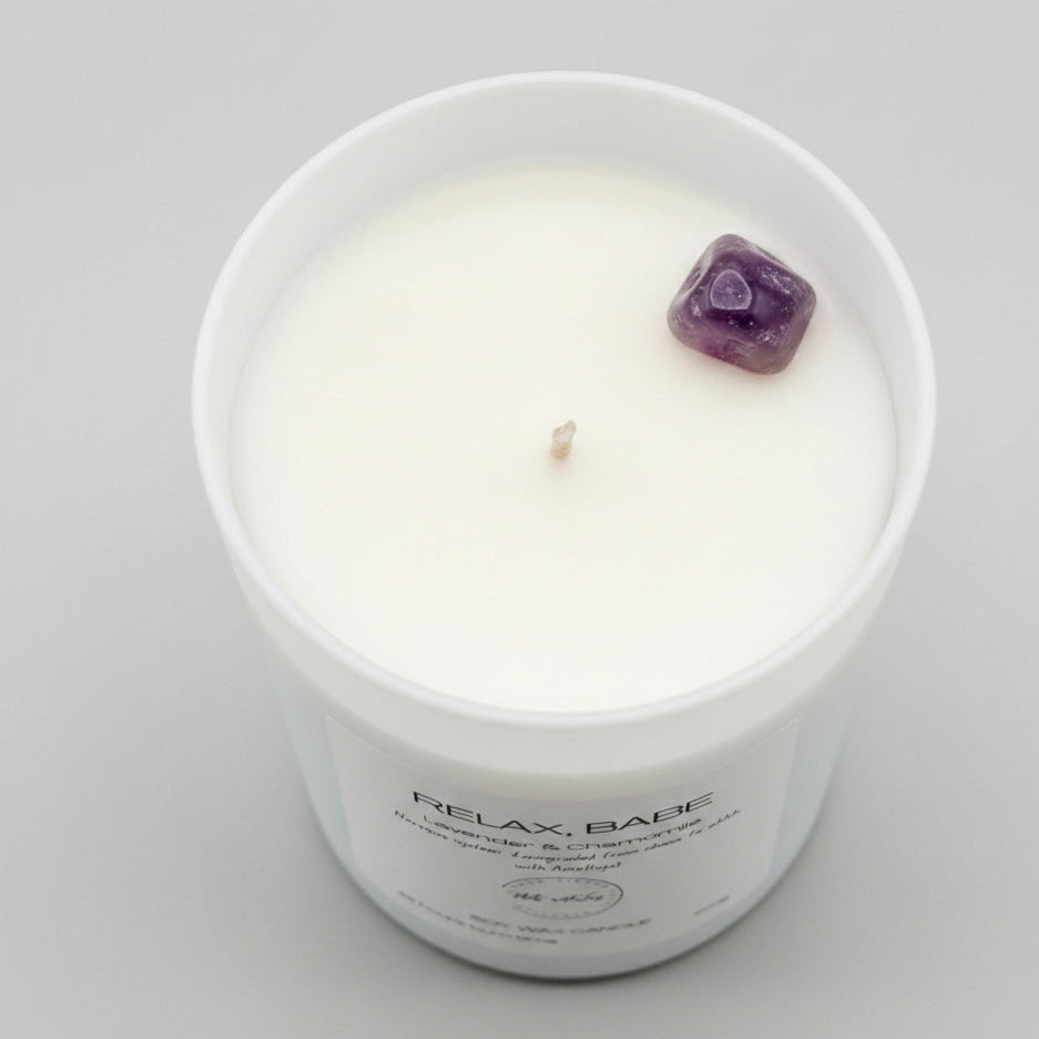 Candle in a white container with a purple crystal on a gray background