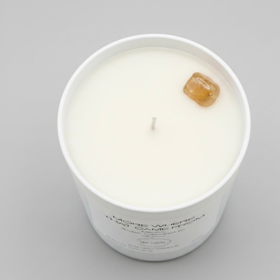 White candle in a glass jar with a label on a gray background